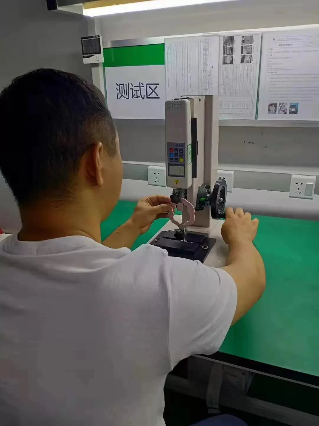 Operator checking a silicone component on a force-testing stand