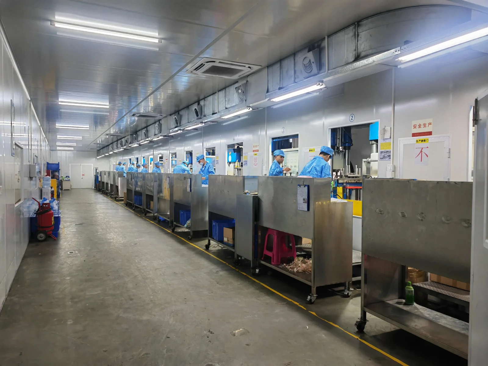 Operators in matching blue uniforms working along the silicone molding press production line