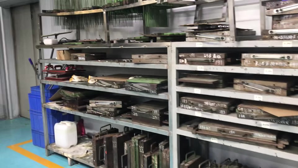 Metal moulds and tooling arranged on multi-level storage racks in the workshop.