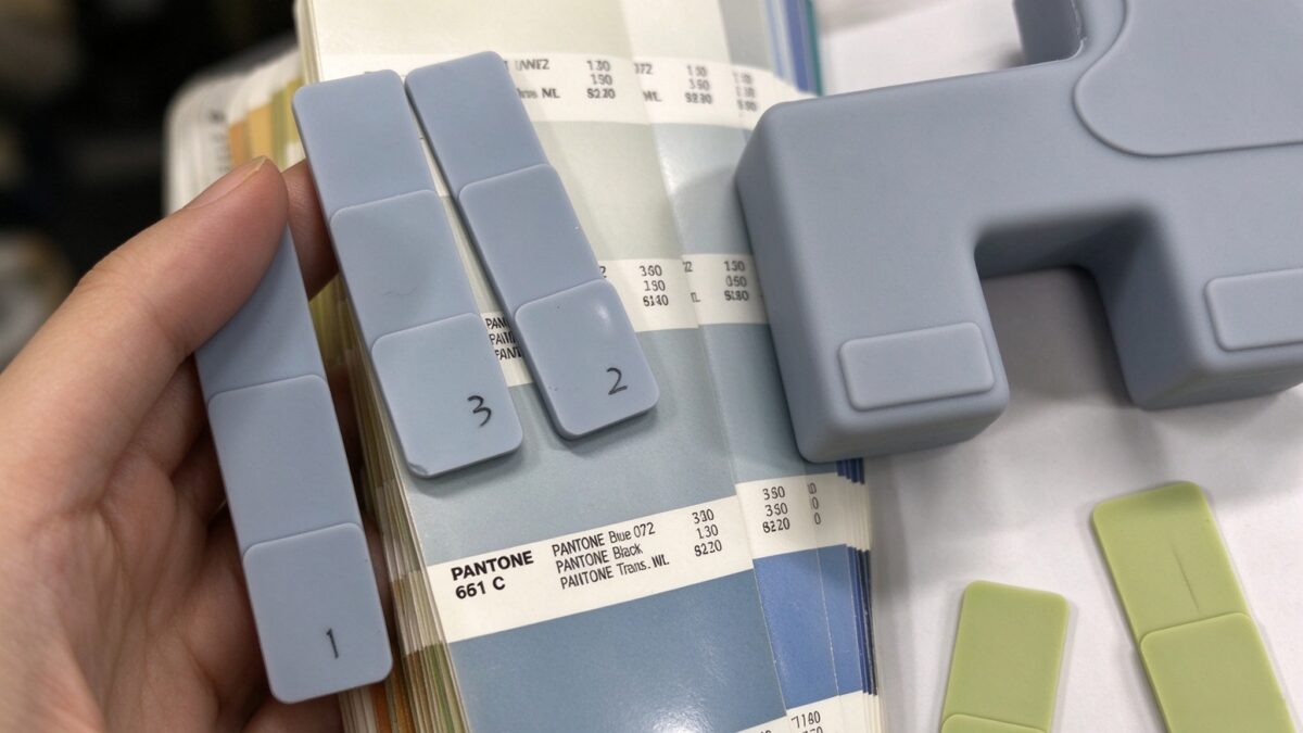 Hand holding numbered silicone color swatches against Pantone card for color matching quality control